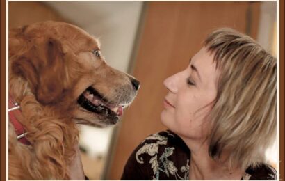 Woman and golden retriever looking at each other closely indoors