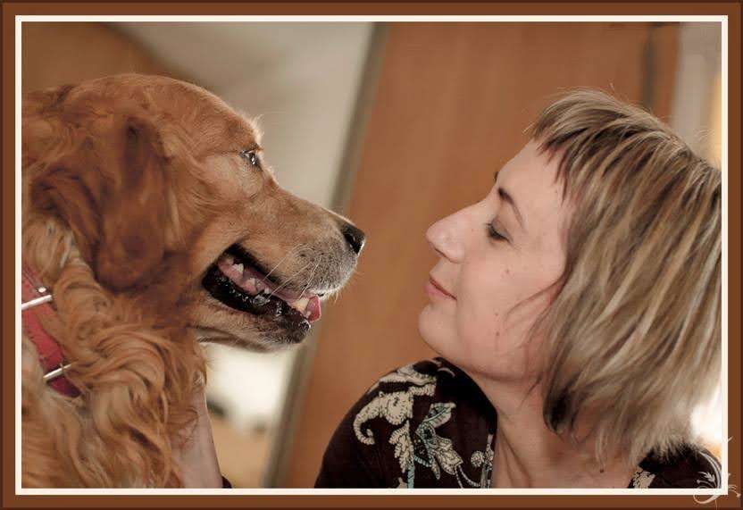 Woman and golden retriever looking at each other closely indoors